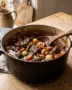 Boeuf bourguignon in een gietijzeren pan met mals rundvlees, champignons, zilveruitjes en wortel in rodewijnsaus